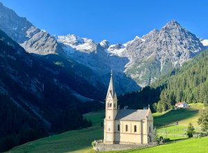 Het iconische kerkje in Trafoi aan de voet van de Stelviopas met besneeuwde alpentoppen tijdens een Ride Up fietsreis.