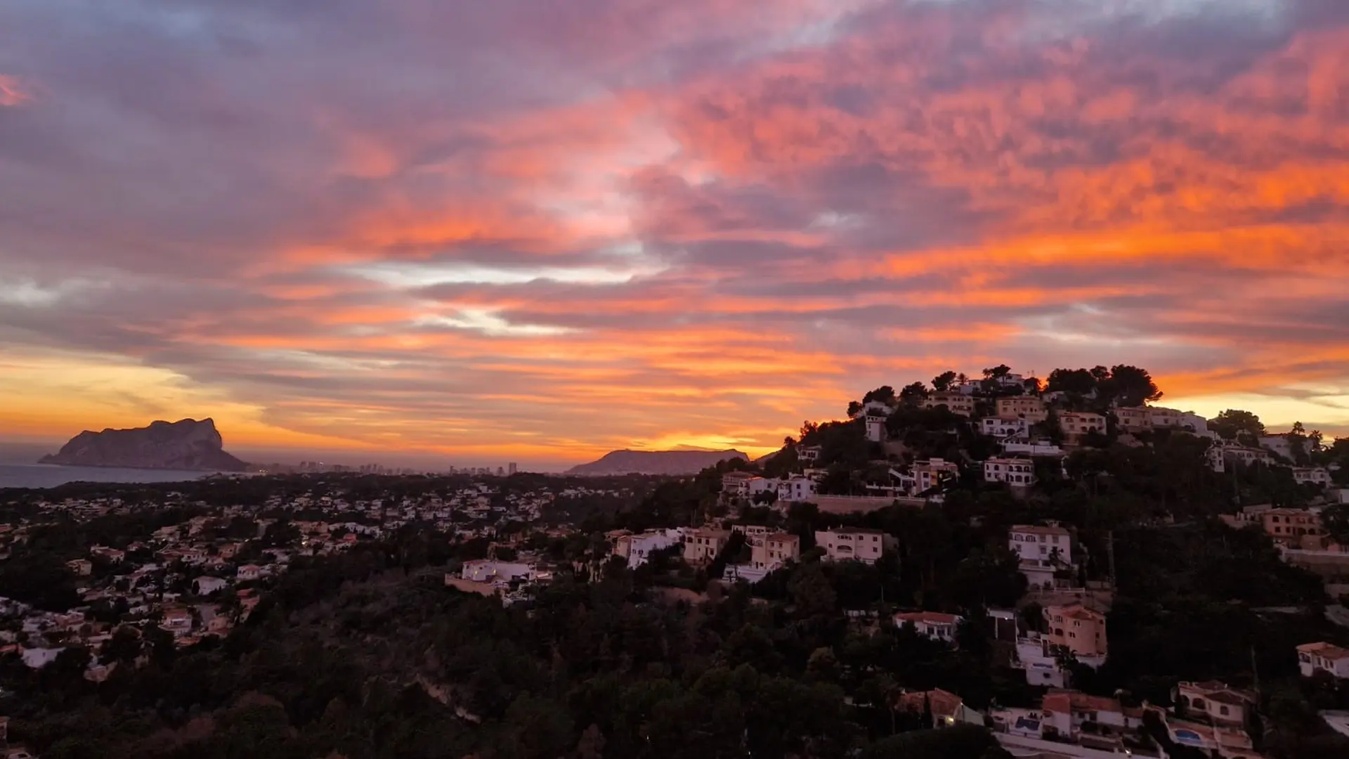 Zonsondergang boven de heuvels van Calpe met de iconische Peñón de Ifach aan de horizon.
