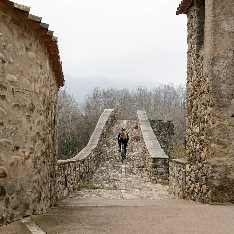 Gravelpad tussen oude stenen muren tijdens een fietsroute bij Girona